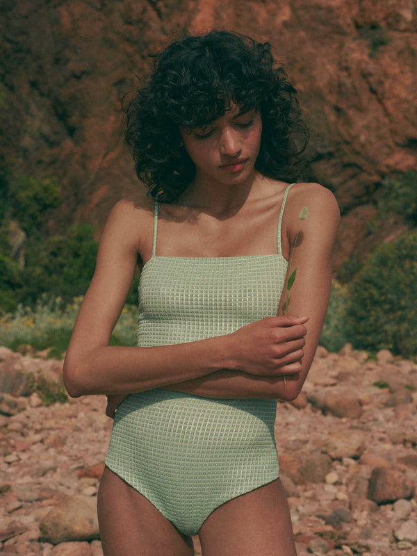 model is wearing green one-piece swimsuit with square neckline and thin straps in jacquard fabric, front view
